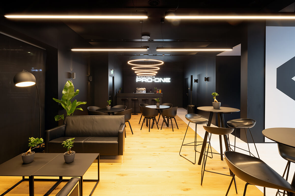 Großzügiger Lounge- und Barbereich mit warmen Holztönen und hochwertigen Materialien im Stellantis Pro One Messestand.