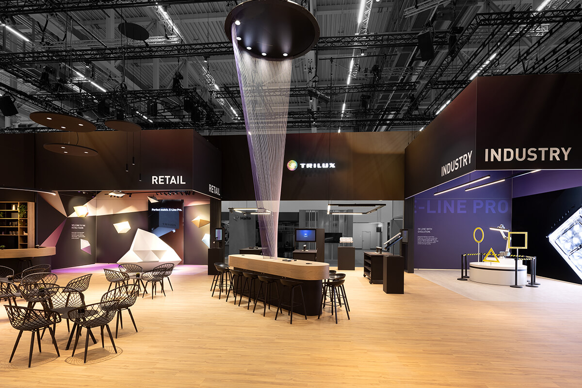 Besucherbereich des TRILUX Messestands in Frankfurt mit interaktiven Lichtanwendungen